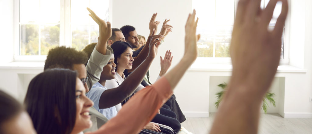 Photo of a diverse group of people raising hands during a training session